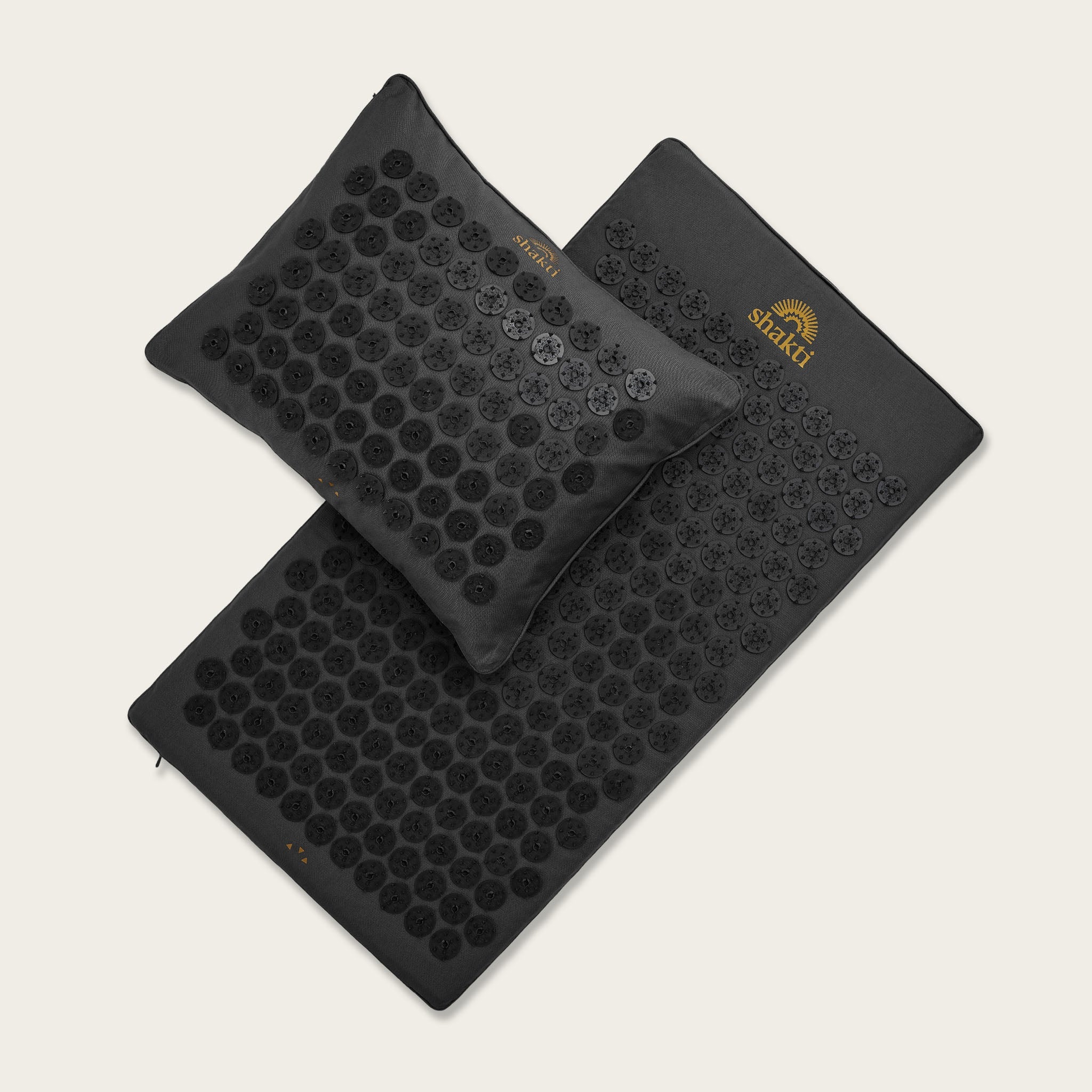 Black acupressure mat and pillow set on a light gray background